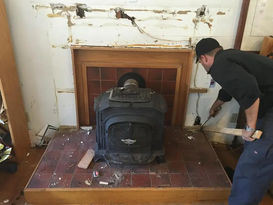 A Top Hat technician removing an old wood stove from a fireplace surround
